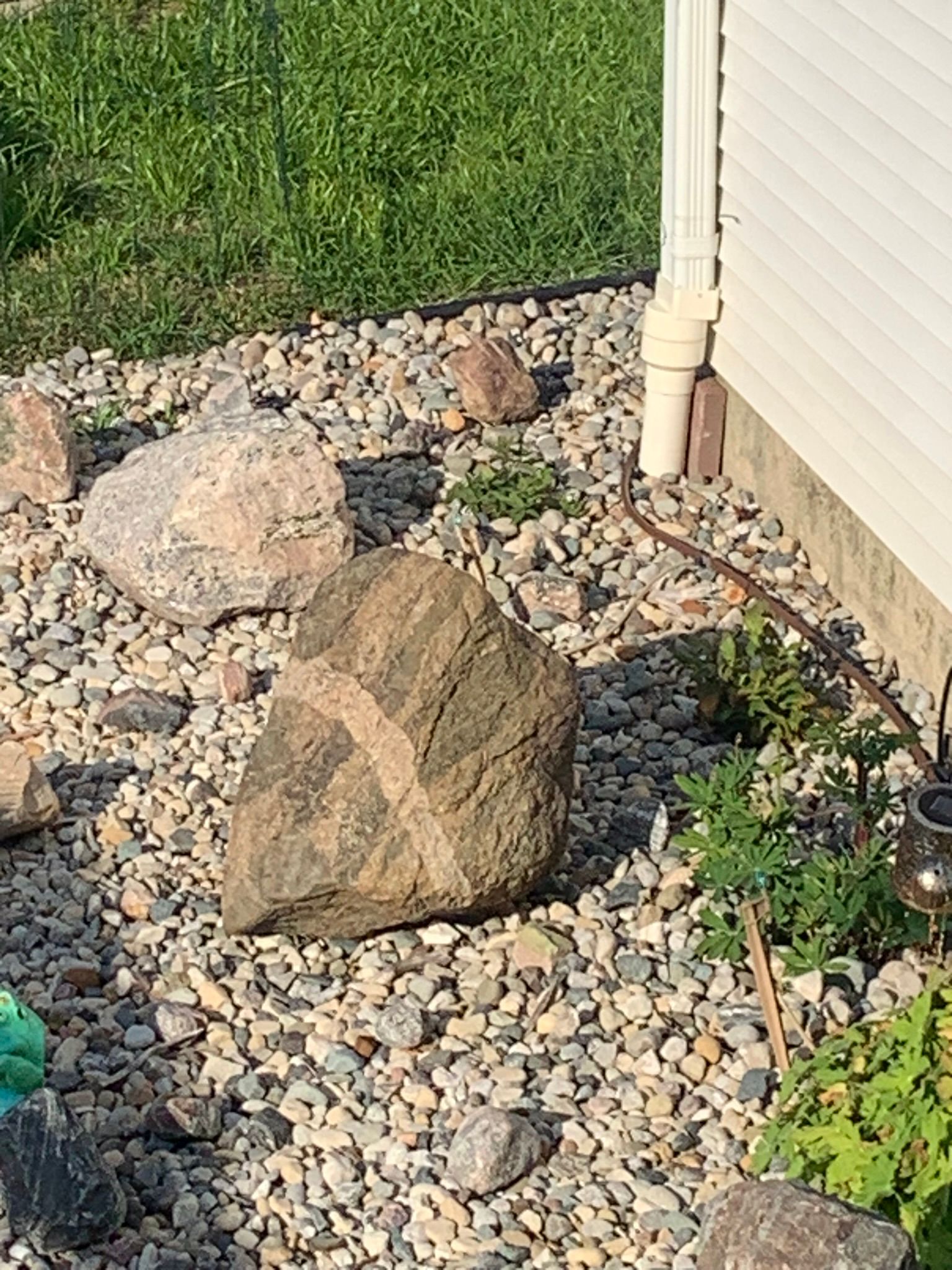 A collection of various-sized landscape rocks sitting on wooden pallets in an outdoor lot under a cloudy sky.