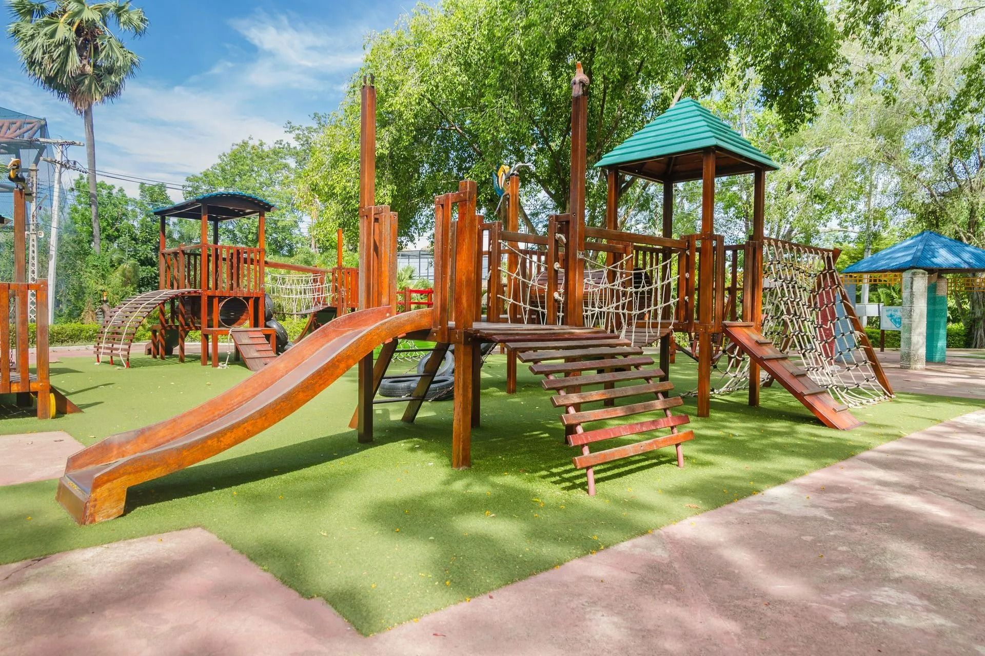 Wooden playground with slides and climbing structures in a sunny park