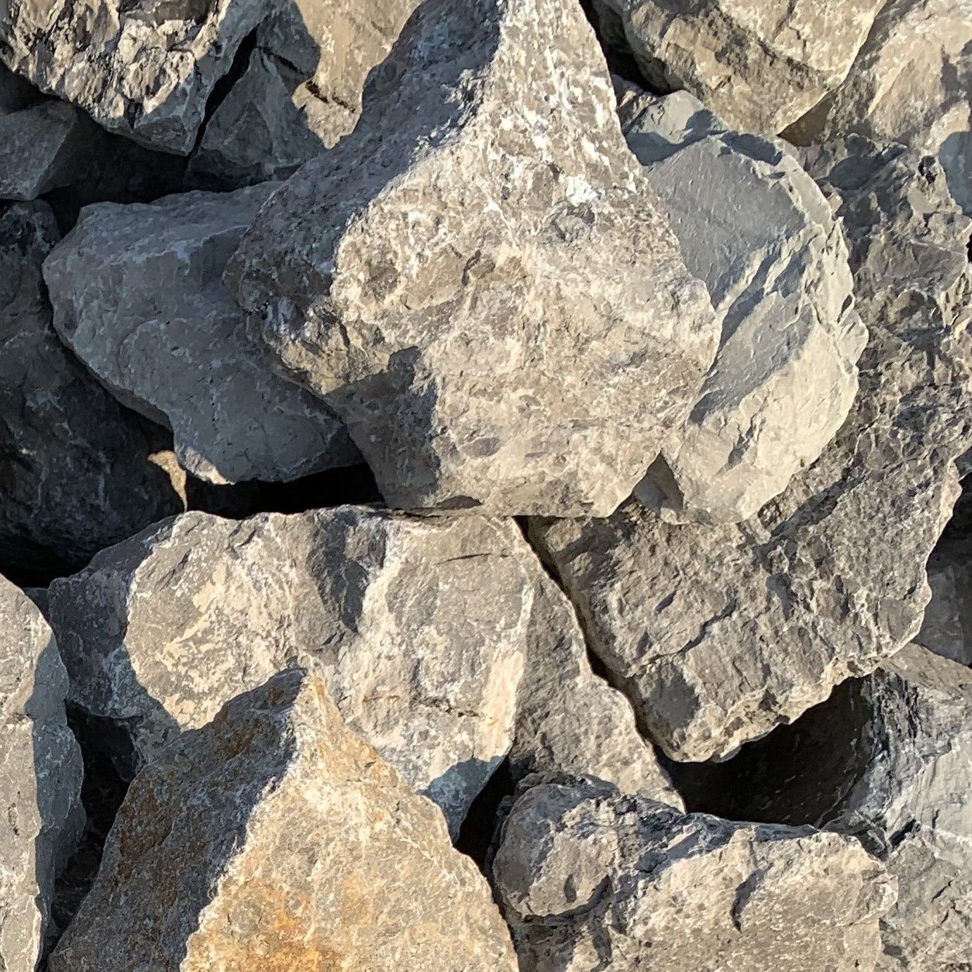 A collection of large, jagged, grey limestone rocks stacked together in natural light.
