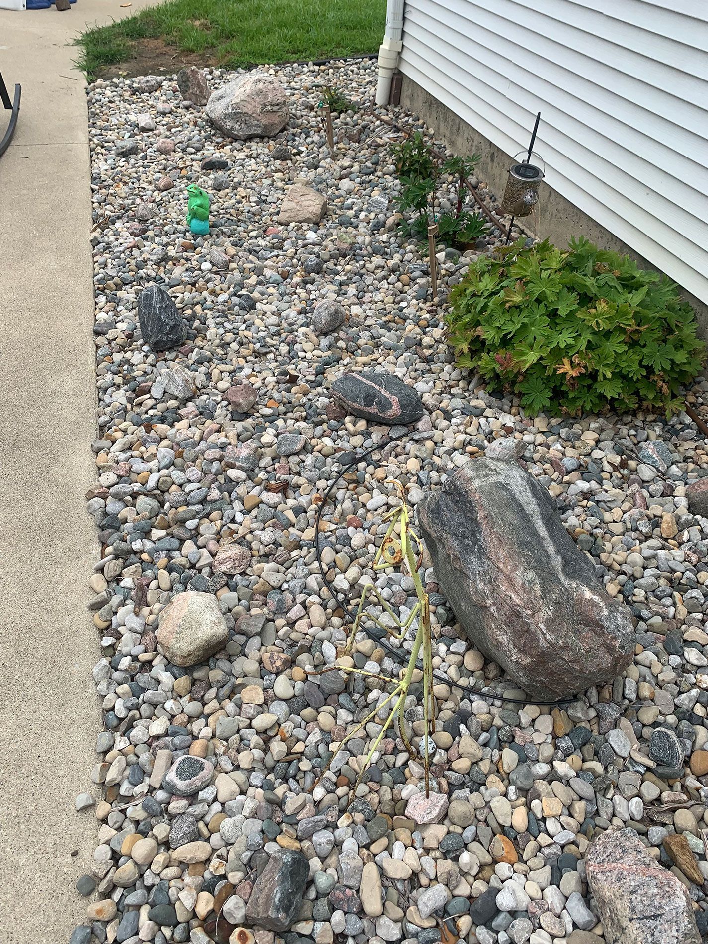 A ground-level view of various smooth, multi-colored river stones and two larger, textured boulders.