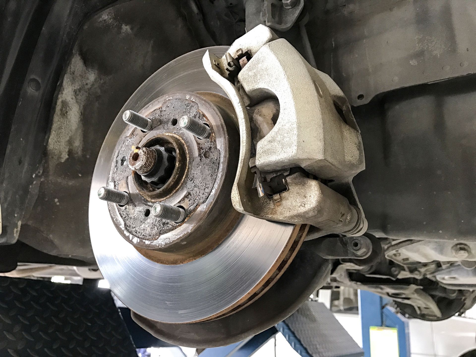 A close-up view of an automobile's disc brake system, including the rotor and brake caliper, mounted on a vehicle.