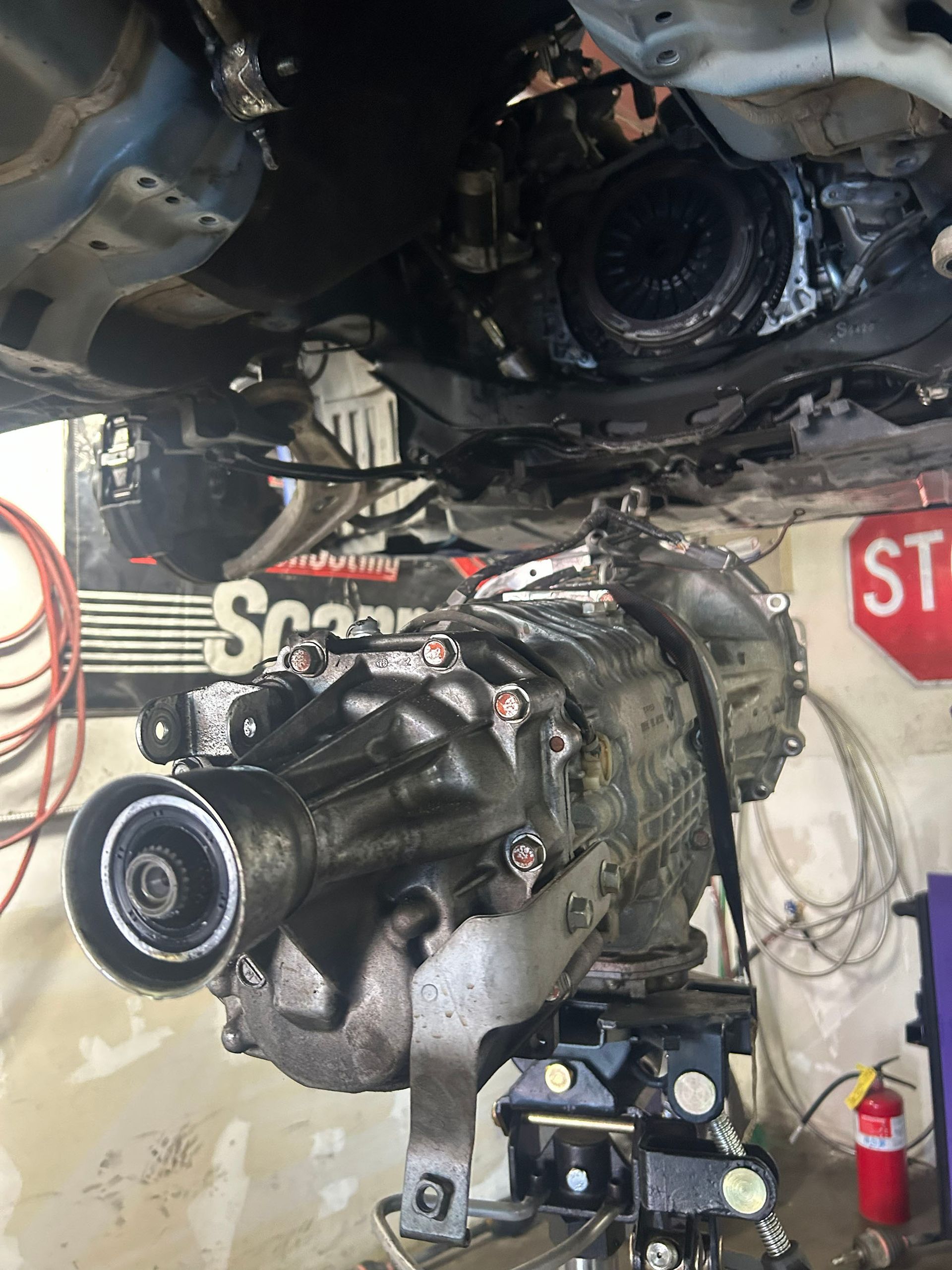 A manual transmission removed from a vehicle, suspended on a transmission jack in a workshop.