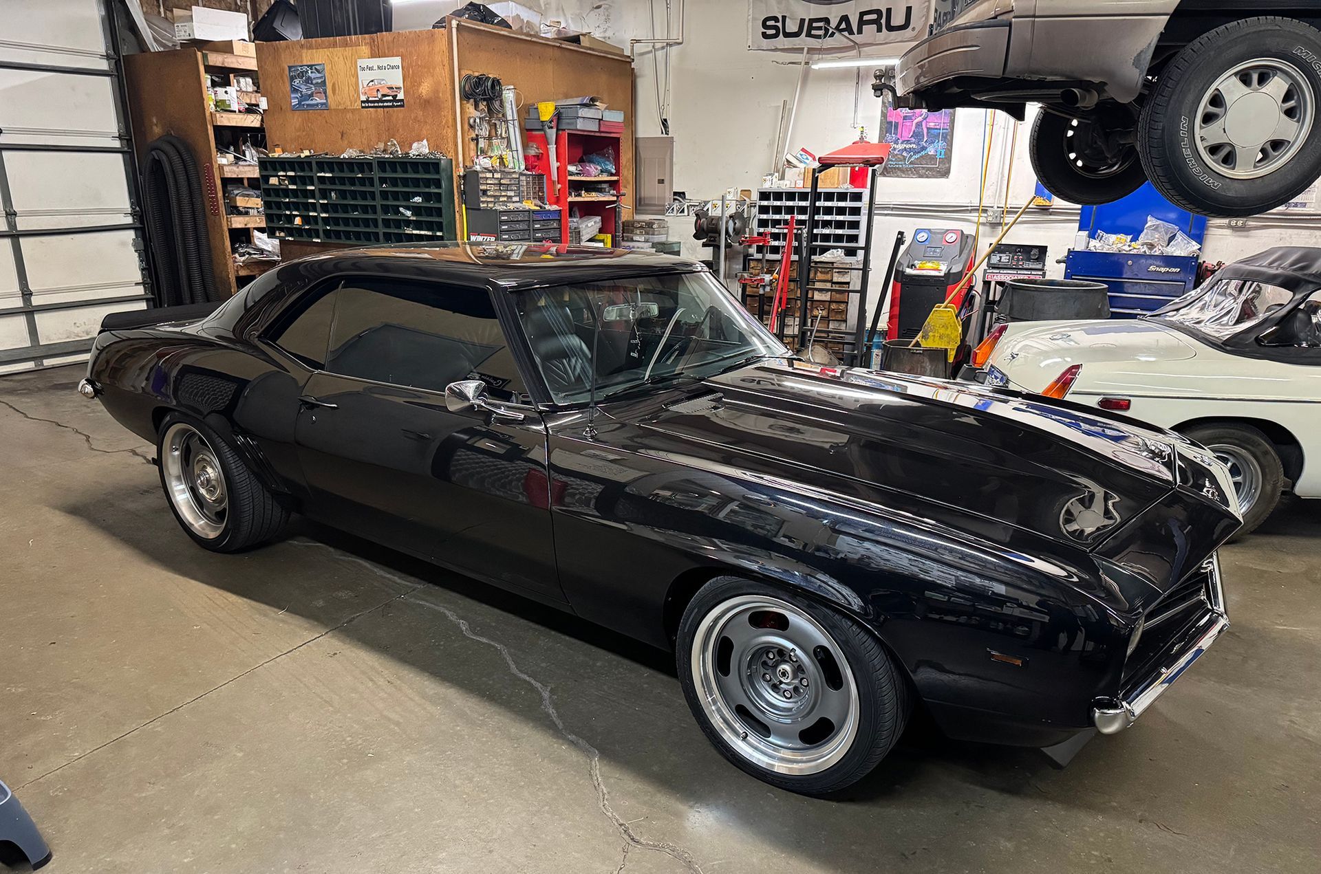 Black classic muscle car in an auto repair shop lift bay