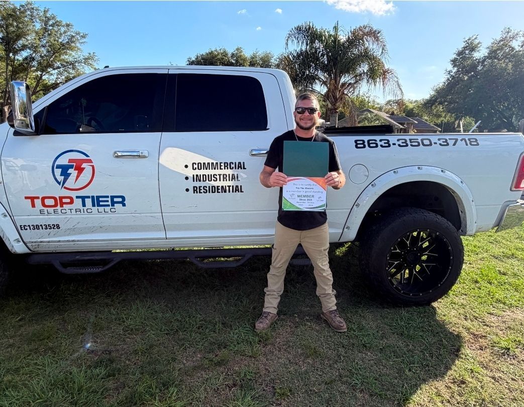 Man standing beside a white pickup truck with a company logo, holding a plaque outdoors on grass.