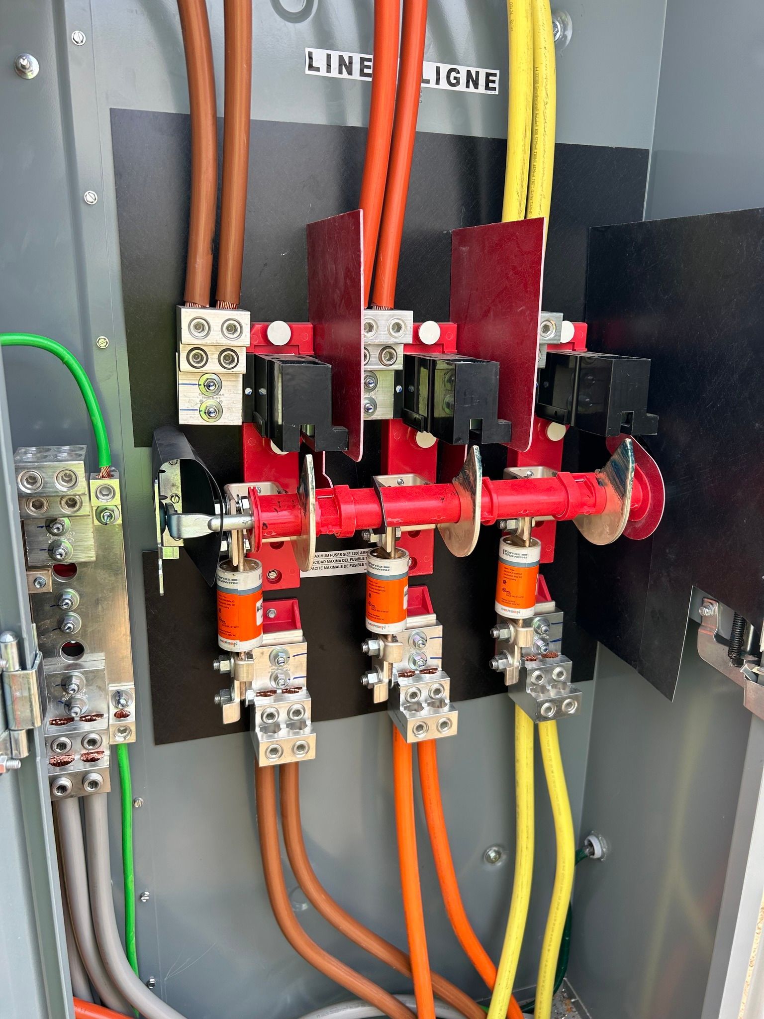 Electrical disconnect switch with three-phase power cables (brown, orange, yellow) and ground wiring inside a metal box.