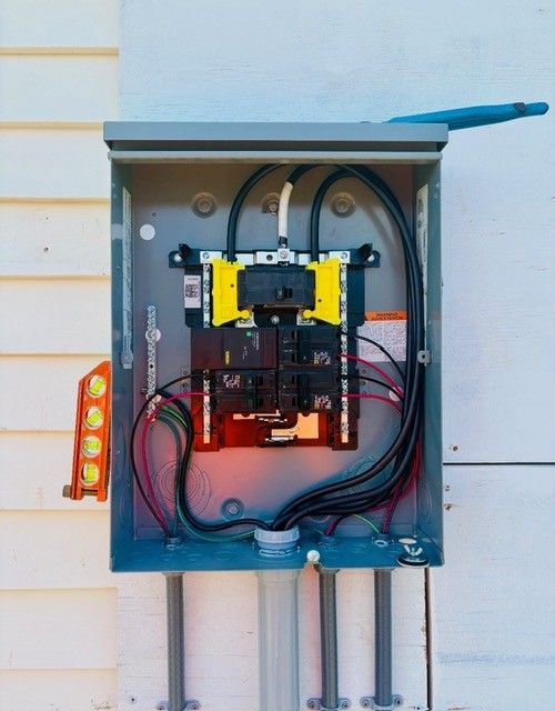 An open electrical service panel mounted on an exterior wall, showing internal circuit breakers, wiring, and a level.