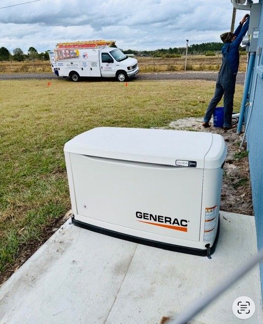A Generac home standby generator sits on a concrete pad outside a building, while a worker services electrical equipment.