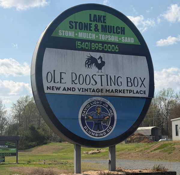 A large round sign for Lake Stone & Mulch, Ole Roosting Box marketplace, and David Light Jr. Inc. plumbing service.