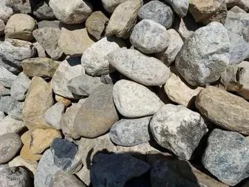 Pile of various-sized river rocks in shades of gray, tan, and cream.