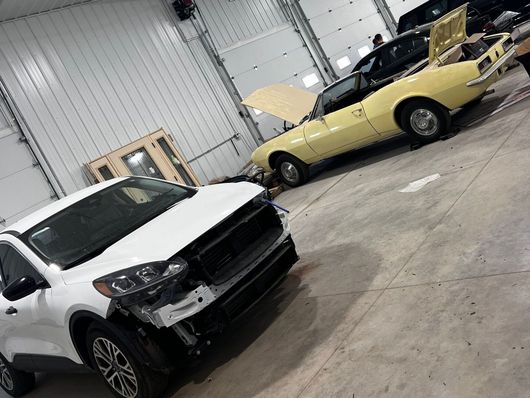 A white car is parked next to a yellow car in a garage.