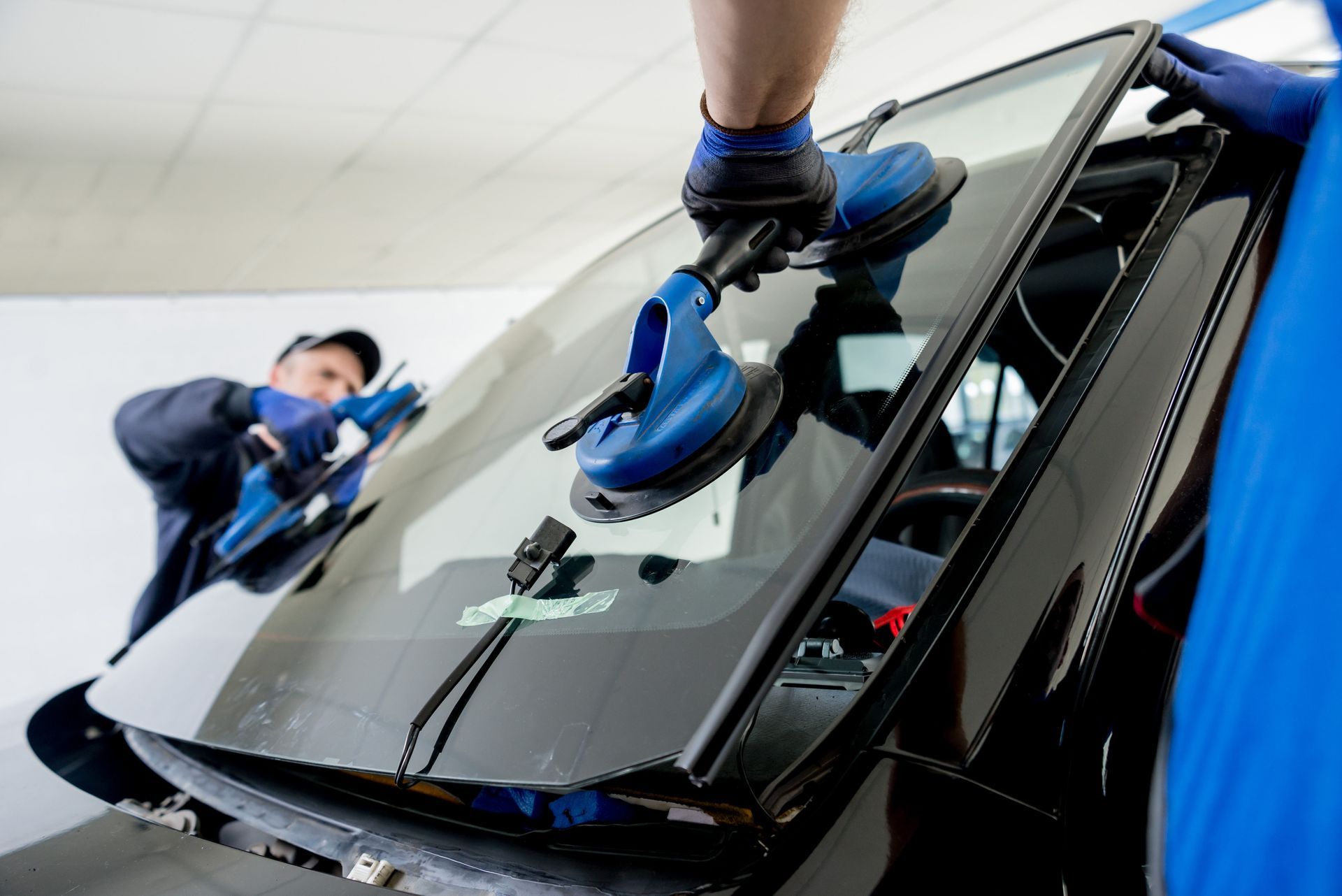 A man is installing a windshield on a car.