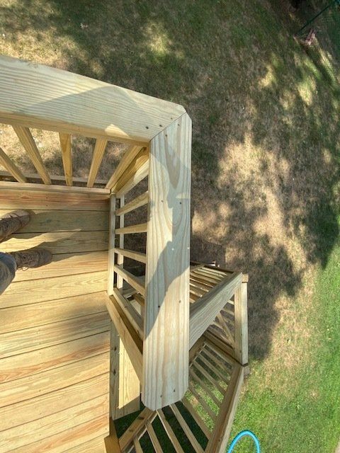 Wooden deck corner with railings; green grass visible in the background.