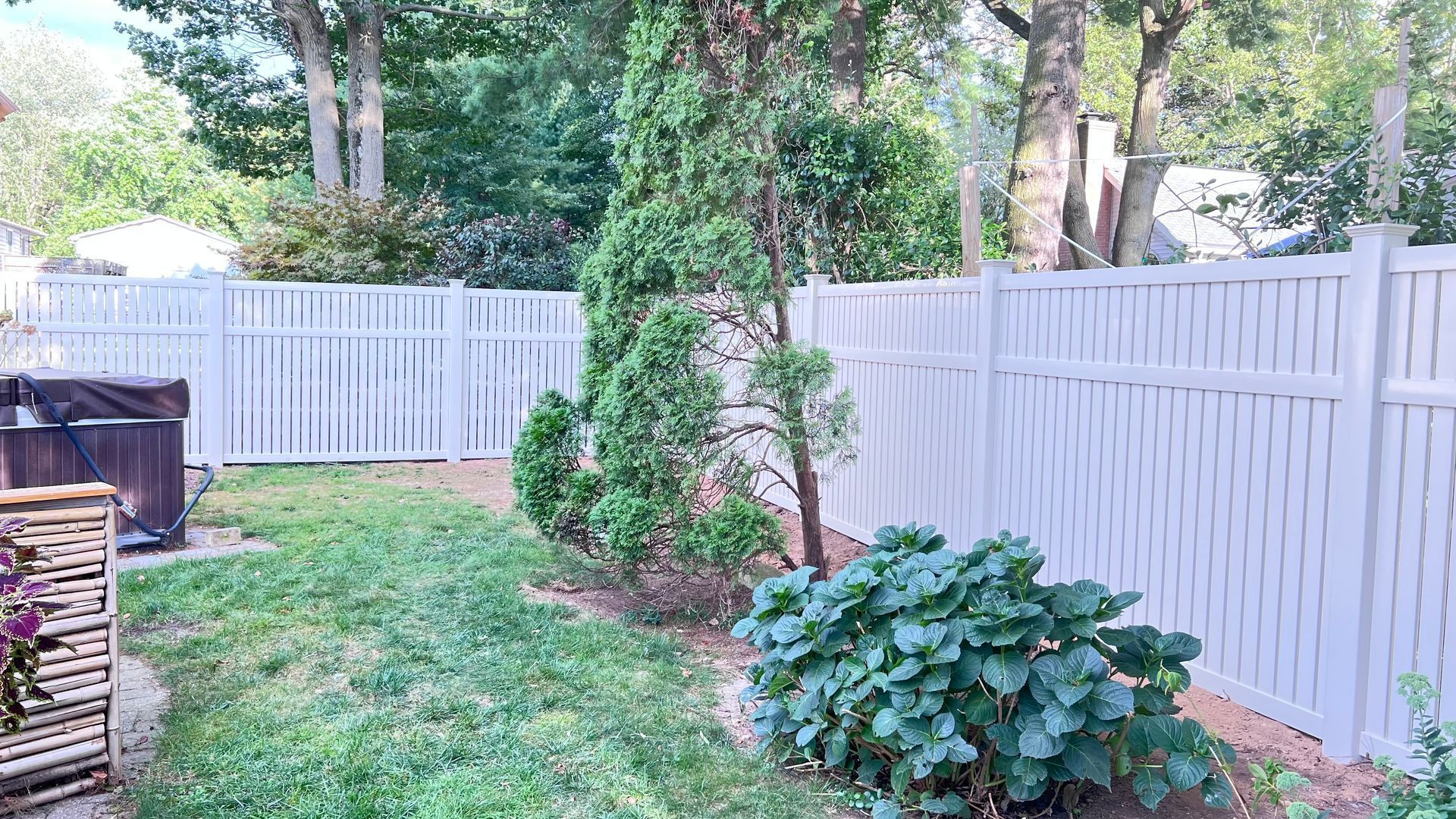 White fenced backyard with a small tree and greenery.
