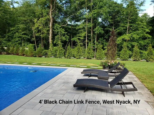 Poolside with lounge chairs on stone patio, green lawn, trees, West Nyack, NY.
