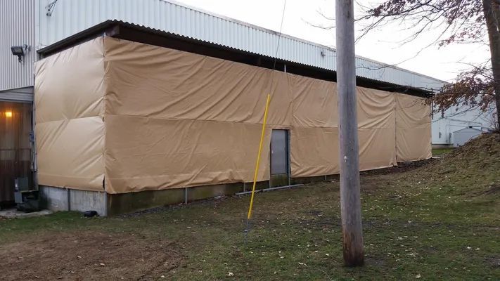 Tan tarp covering the side of a building; a yellow-framed door is visible.