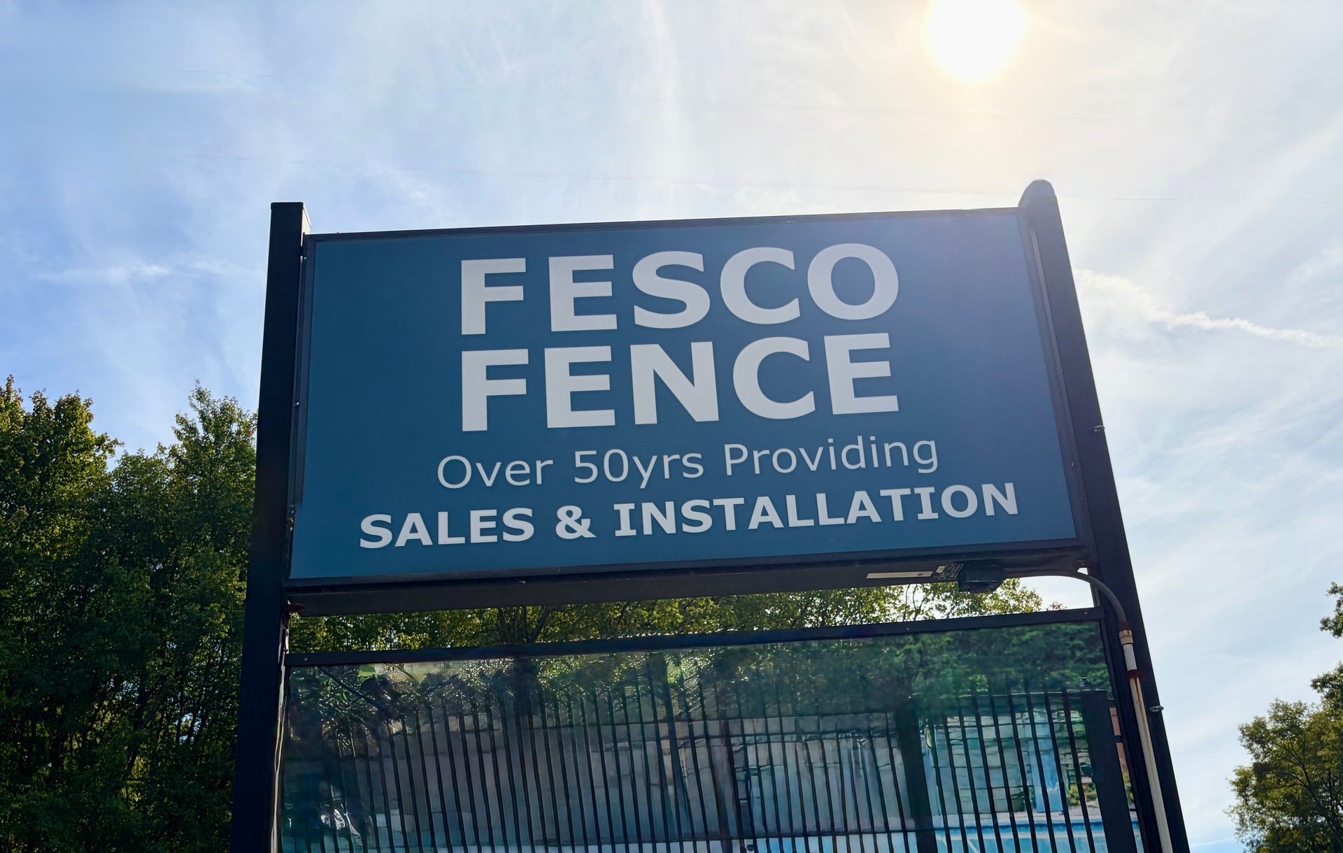 Sign for Fesco Fence, blue background, white text.  Says 