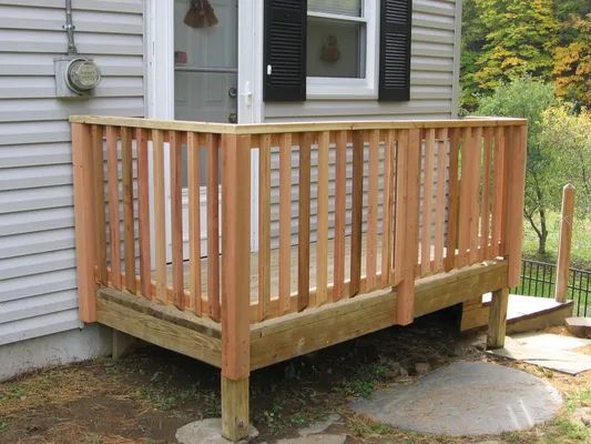 Wooden porch with railing and steps in front of a house.