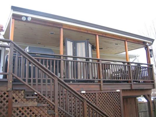 Wooden deck with stairs, covered patio, outdoor grill, and railing.