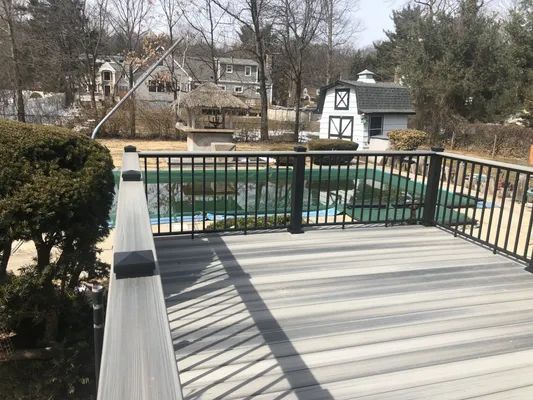 Deck overlooking a swimming pool and yard with gazebo and small barn.