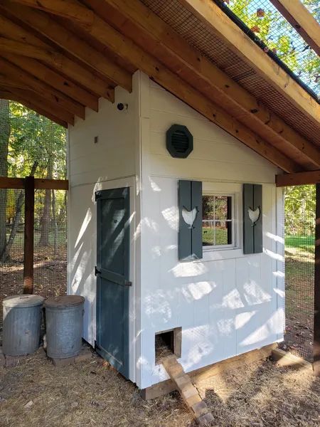 White and teal chicken coop with wood roof.