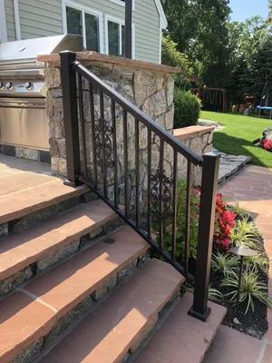Outdoor staircase with brown metal railing and stone accents.