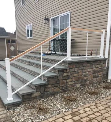 Stone steps and patio with white railing, wood top rail, and a sliding glass door.