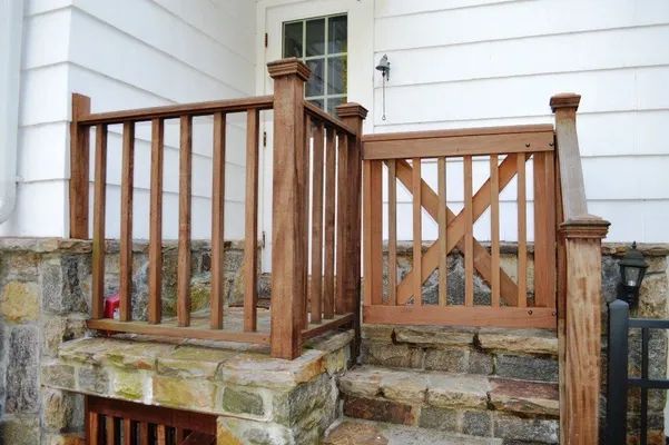 Wooden railing and gate on stone steps leading to a white door.