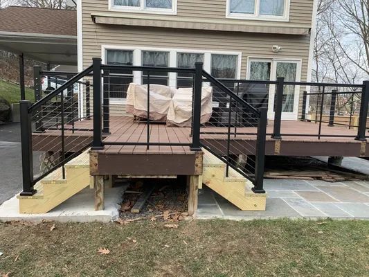 A composite deck with black railing and steps leading up to an outdoor seating area.