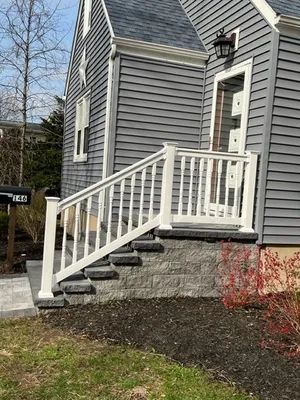 White handrail and steps leading to a gray house's front door with dark gray siding.