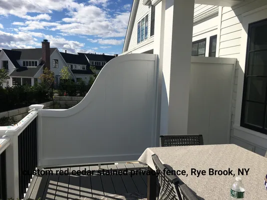 White privacy fence on a deck, with a house in the background. Location: Rye Brook, NY.