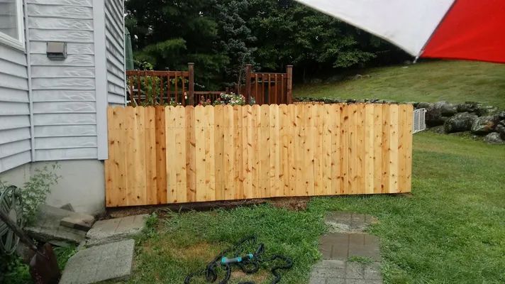 Wooden fence in a yard next to a house and grass.