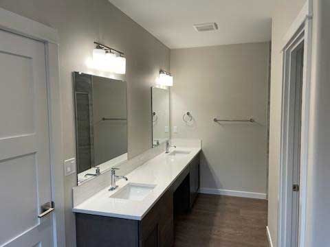 Modern bathroom with dual vanity, gray cabinets, white countertop, and two rectangular mirrors.
