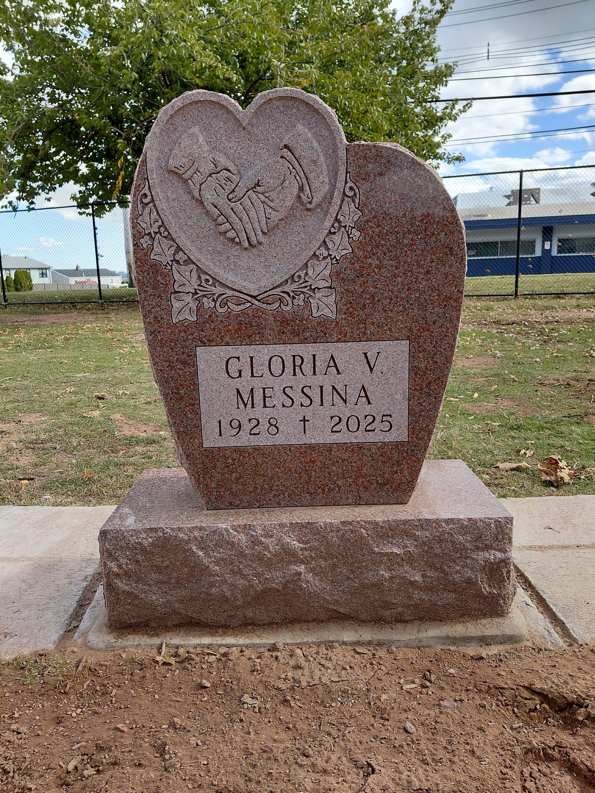 Heart-shaped memorial stone for Gloria V. Medina in a grassy outdoor setting.