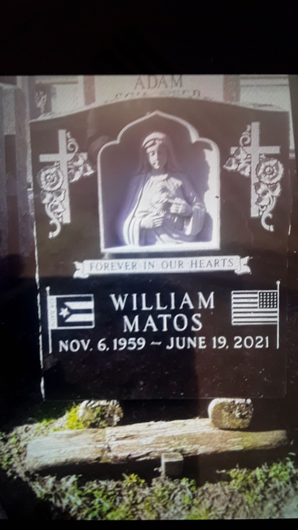 Black memorial headstone for William Matos with portrait, dates, and decorative symbols
