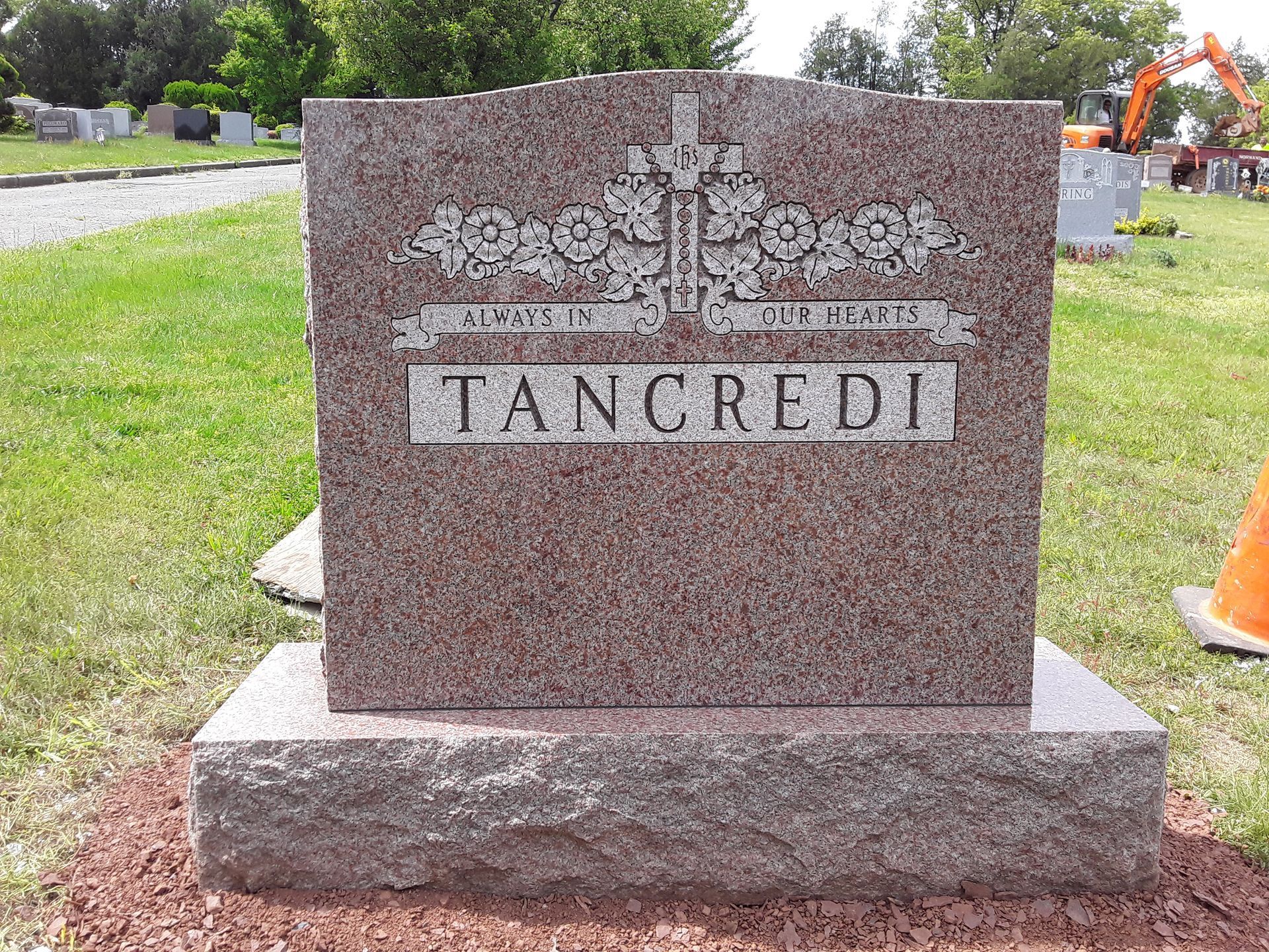 Granite grave marker engraved “TAN CREDI” with floral emblem in a cemetery