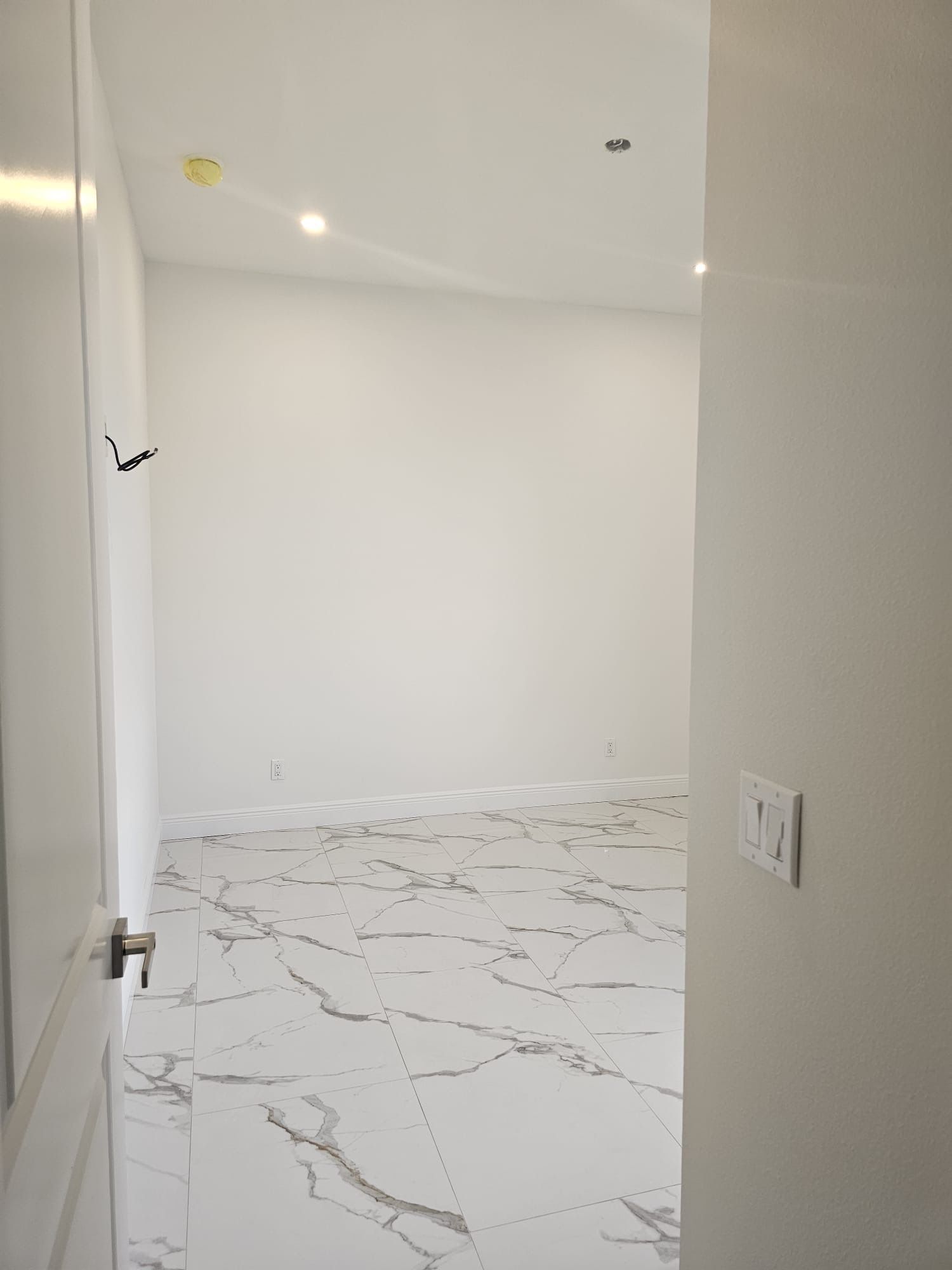 An empty room with marble floors and white walls.