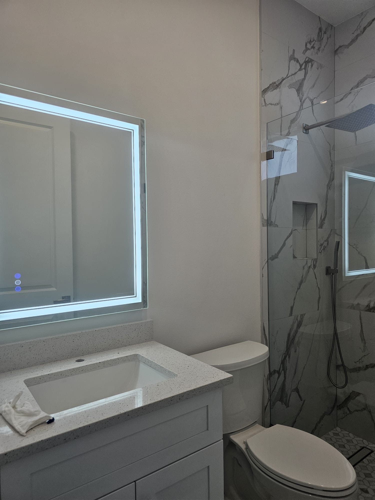 A bathroom with a toilet , sink , mirror and shower.