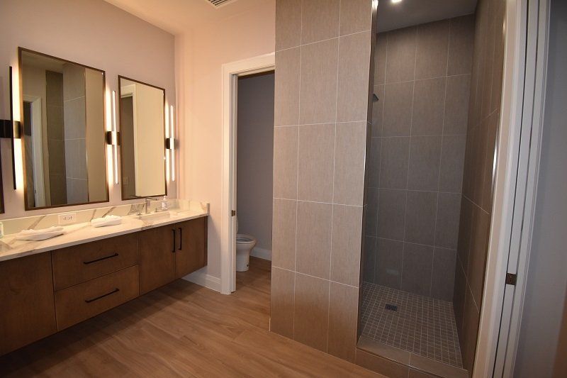 A bathroom with two sinks and a walk in shower.