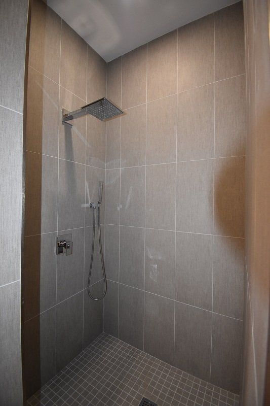 A bathroom with a walk in shower and a shower head.