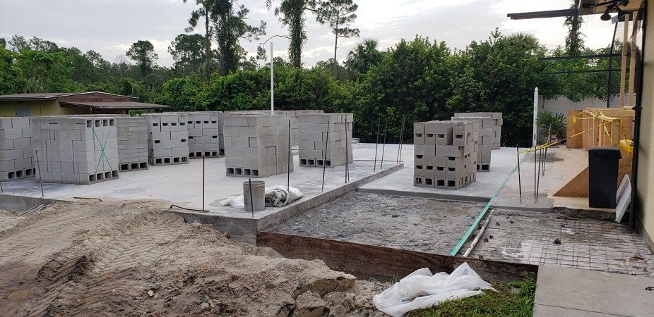 A lot of concrete blocks are sitting on top of a dirt field.