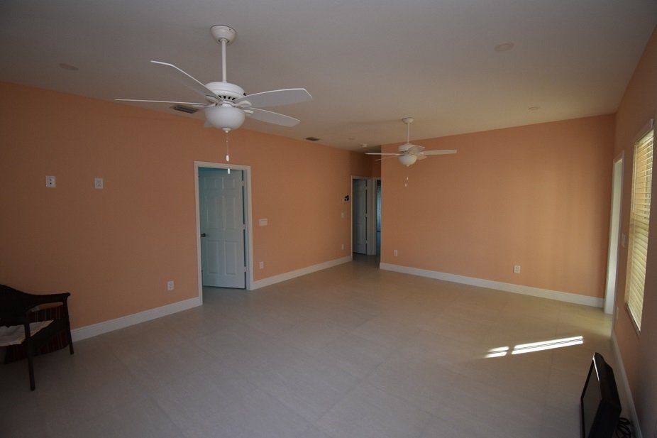 An empty living room with two ceiling fans and a television.