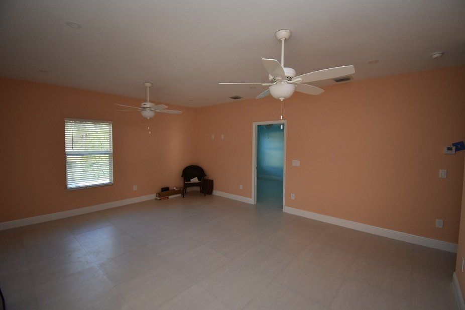 An empty living room with two ceiling fans and a chair.