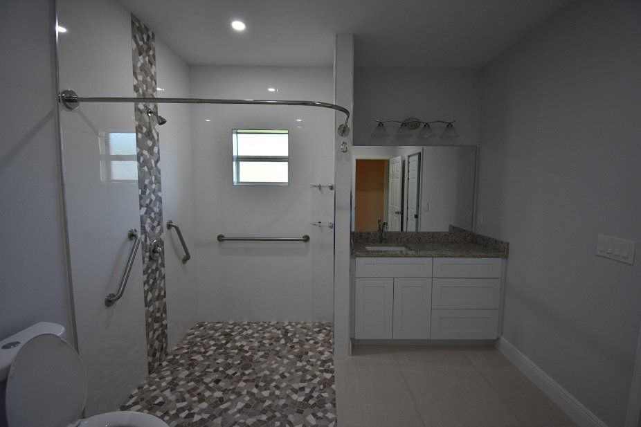 A bathroom with a walk in shower, sink and mirror.