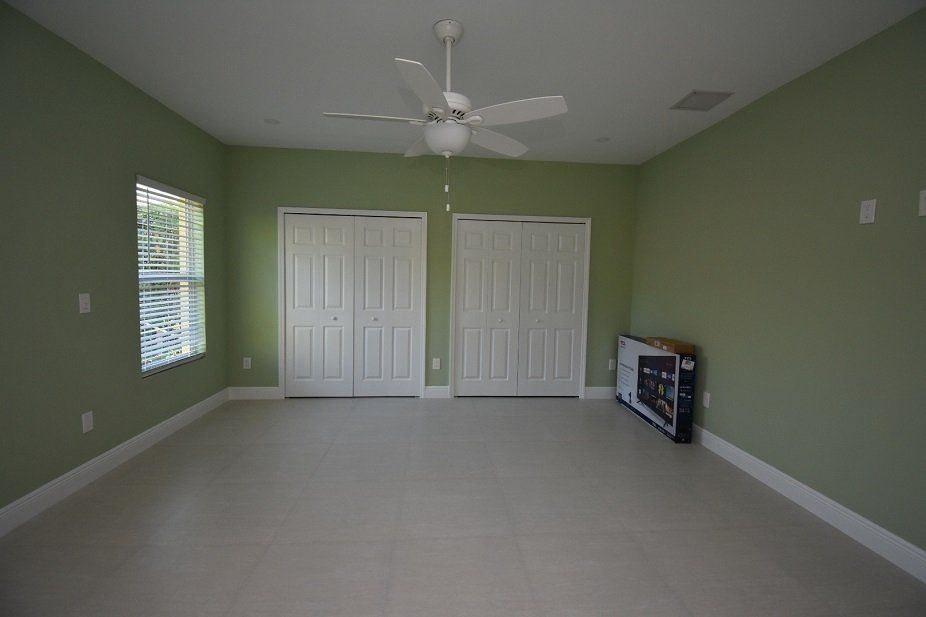 An empty room with two closets and a ceiling fan.