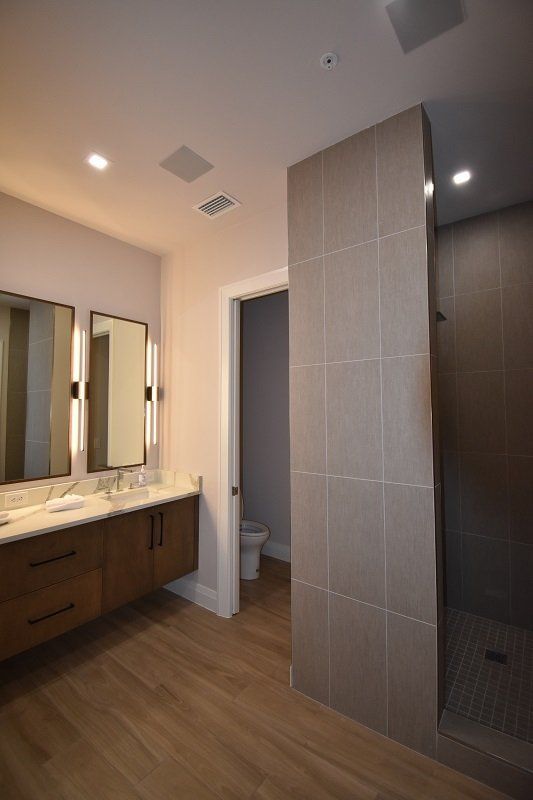 A bathroom with two sinks, a toilet, and a walk in shower.