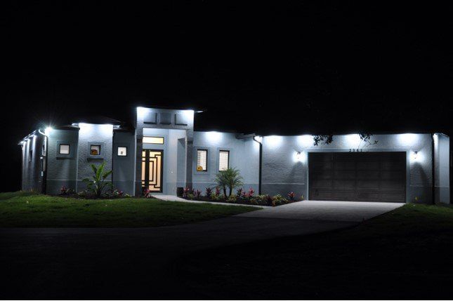 A modern house is lit up at night with lots of lights.