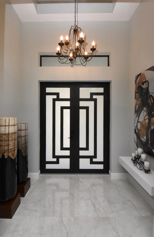 A hallway with a black and white door and a chandelier