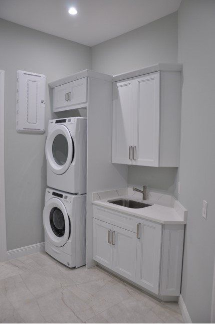 A laundry room with a washer and dryer stacked on top of each other and a sink.