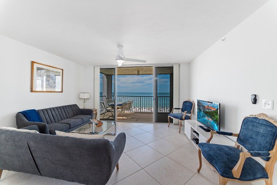 A living room with a couch, chairs, and a television.