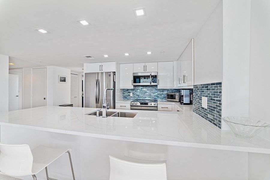 A kitchen with white cabinets, stainless steel appliances, a sink, and a refrigerator.